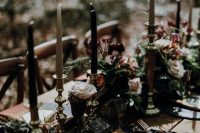 a moody and refined Halloween wedding table with gold napkins, black and white candles, greenery, succulents and blush roses