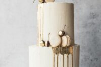 a neutral textural wedding cake with gold drip, matching macarons, gilded cherries and willow branches is amazing