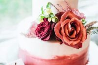 a pretty ombre pink wedding cake topped with burgundy, red and blush ones and greenery is ideal for Valentine weddings