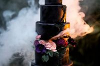 a purple and black glitter wedding cake with blush and purple blooms is a refined and chic idea for Halloween