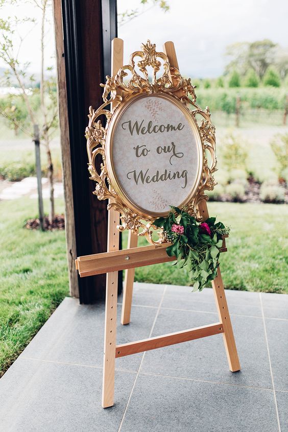 a refined fairy-tale wedding sign in an oranted frame with greenery and bold blooms is a lovely decor idea for a fairy-tale wedding