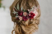 a refined low updo with twists and some waves down and bold blooms – fuchsia, blush and pink flowers, greenery