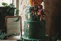 a romantic black wedding cake with gold leaf, sugar blooms, bright flowers and greenery for a Halloween wedding