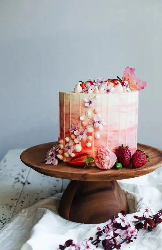 a romantic ombre pink wedding cake with creamy drip, meringues, pink blooms and petals is beautiful