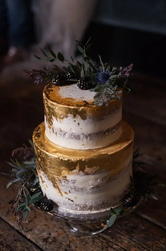 a semi naked wedding cake with gold foil, blackberries and thistles for a fall wedding