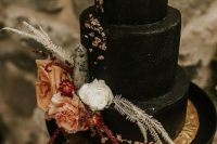a stunning black textural wedding cake with gold leaf, dried and fresh blooms, dried leaves and some rocks for Halloween