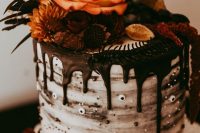a stylish and chic Halloween wedding cake with chocolate drip, googly eyes, berries and fruit plus bright blooms