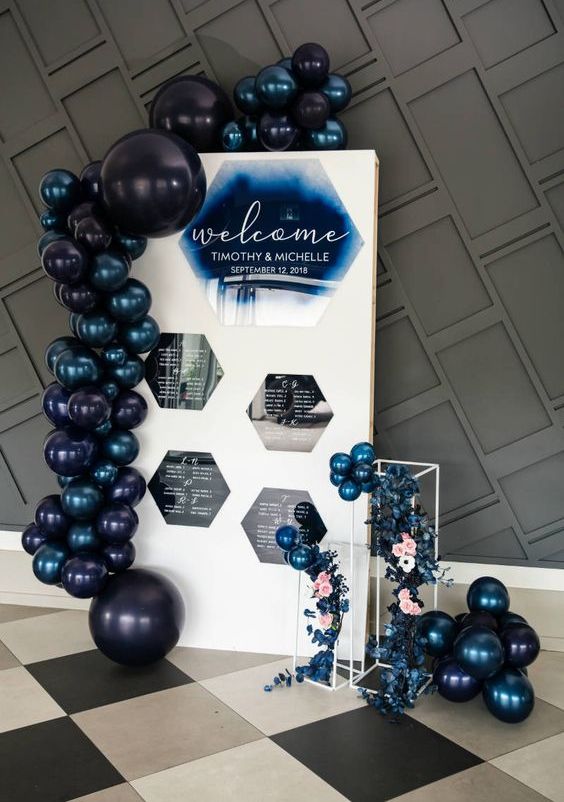 a stylish contemporary seating chart with hexagons, mignight blue and black baloons and some blue flowers