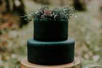 a stylish modern Halloween wedding cake in black and gold, with greenery and wildflowers on top is refined