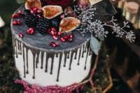 a stylish white wedding cake with grey drip, fresh berries, fruits and leaves and blooms is ultimate for Halloween