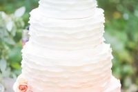 a subtle ombre ruffle wedding cake fro white to blush and with peachy blooms is a cool idea for a spring or summer wedding