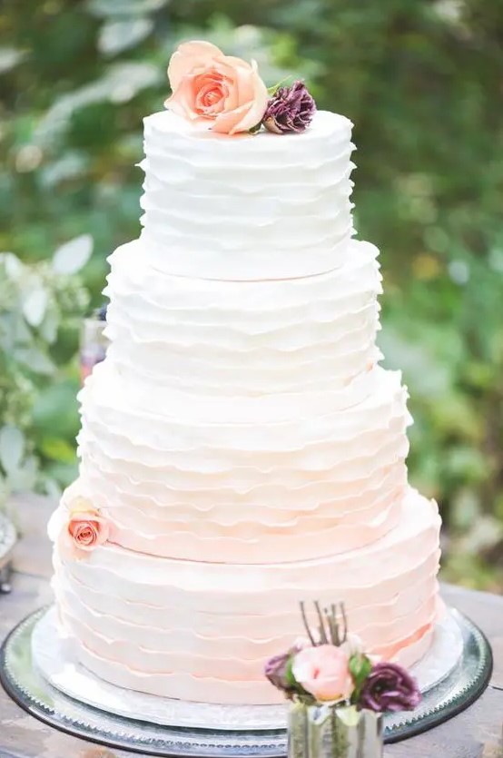 a subtle ombre ruffle wedding cake fro white to blush and with peachy blooms is a cool idea for a spring or summer wedding