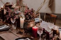a sumptuously colored Halloween wedding tablescape with black plates, fuchsia and purple blooms and grasses and red candles
