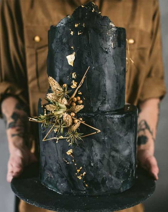 a textural black grey buttercream wedding cake with gold leaf, dried blooms and grasses and twigs is very refined