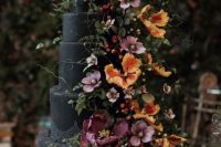 a very elegant and refined black wedding cake with purple, pink and orange sugar and usual blooms and greenery