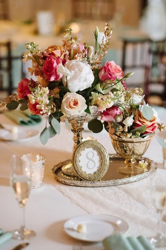 a vintage-inspired centerpiece of a gold tray, a picture frame, a duo of vases with blooms for a stunning vintage wedding