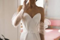 a white strapless jumpsuit paired with sheer long gloves with volume for a modern and refined bridal look