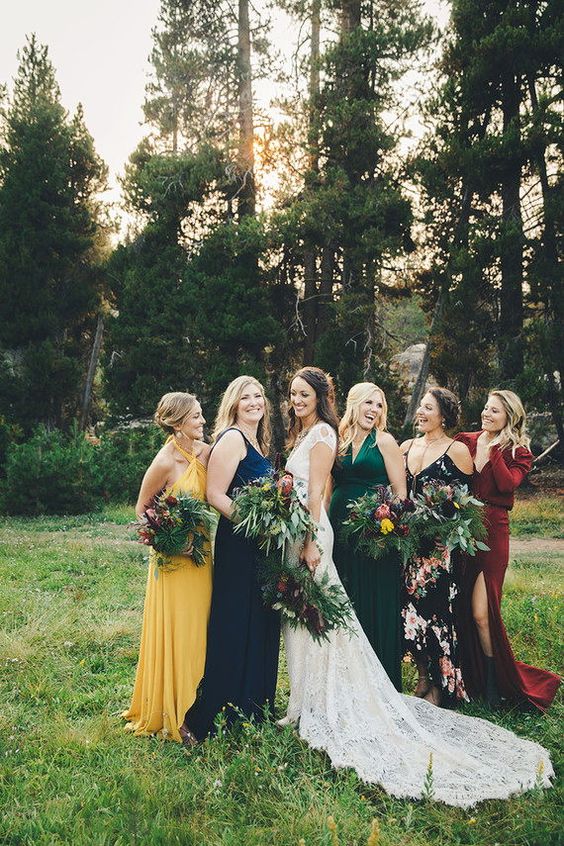 amazing mismatching bridesmaid maxi dresses in green, yellow, navy, burgundy and black, with a floral print for a boho fall wedding