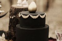 an elegant black haunted wedding cake with sugar patterns and a silver pear on top is a very stylish idea