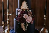 an elegant black wedding cake with gold leaf, burgundy and blush sugar blooms and greenery for Halloween