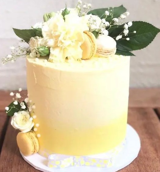 an ombre yellow wedding cake with textural buttercream, white and yellow blooms, macarons and foliage is a bold and cool idea