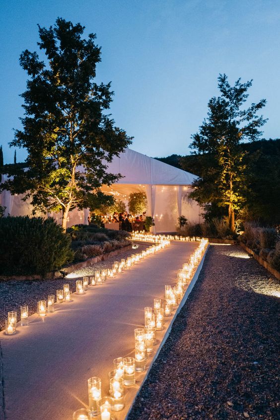 glasses with floating candles lining up the aisle look very chic, beautiful and romantic and add elegance to your walkway