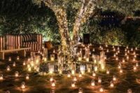 lots of candle lanterns and candleholders and string lights covering the tree make this space look really magical