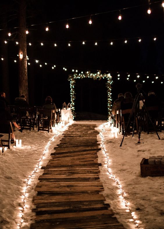 Edison bulbs and string light lining up the aisle and forming a wedding arch plus additional candles for a romantic and ultimate night ceremony