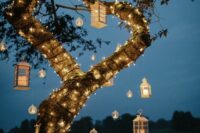 string lights, candleholders and candle lanterns hanging down turn your tree into a magical piece that illuminates everything