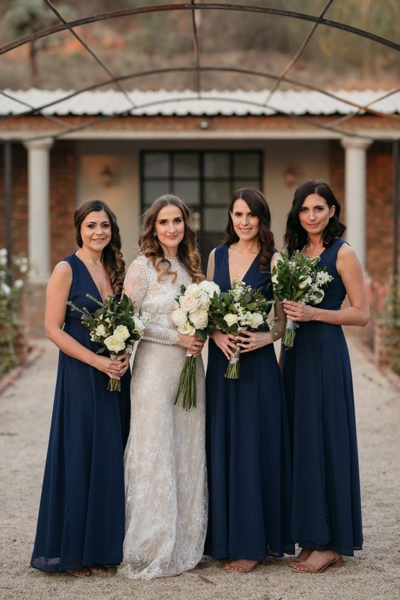 stylish midnight blue bridesmaid dresses with thick straps and deep plunging necklines plus nude heels