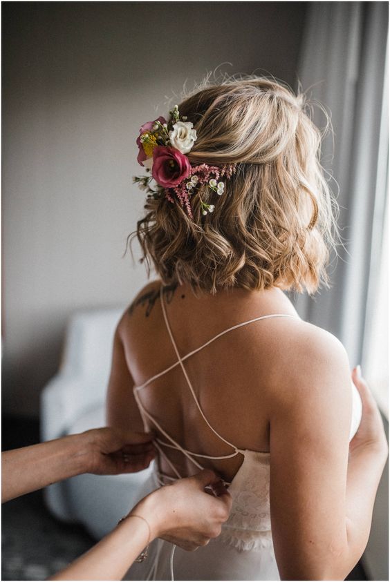 wavy half updo with pink and white blooms and some greenery is a beautiful solution for a bride with medium length hair