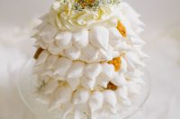 a beautiful meringue wedding cake with fresh fruits, whipped cream and greenery on top is amazing