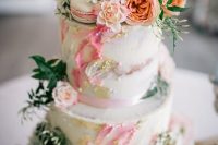 a beautiful spring or summer two-tier wedding cake with bright watercolors, gold, pearls, fresh blooms and greenery and a calligraphy topper