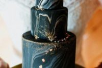 a black and grey marbleized wedding cake with gold glitter and foil