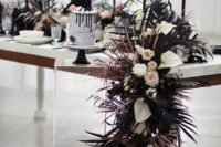 a black and white wedding tablescape with a cascading textural runner, black candles and a marble wedding cake