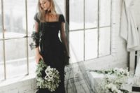 a black sheath wedding dress with cap sleeves, a black veil with a lace trim, a necklace
