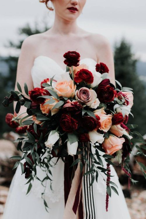 a bold Halloween wedding bouquet with burgundy, dusty pink, orange blooms, usual and dark foliage and striped ribbons