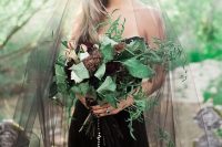 a catchy dark bloom wedding bouquet with large leaves and more greenery, with an embellished wrap