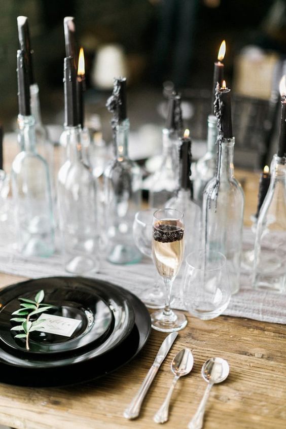 a chic modern gothic table setting with an airy runner, black plates, black candles in bottles