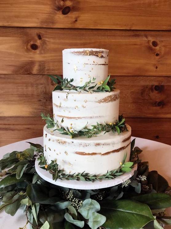 a chic naked wedding cake with gold leaf and greenery is a cool piece for many weddings, not only a rustic one