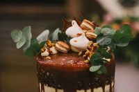 a chocolate naked wedding cake with caramel drip, nuts, meringues, nuts and eucalyptus is a beautiful option