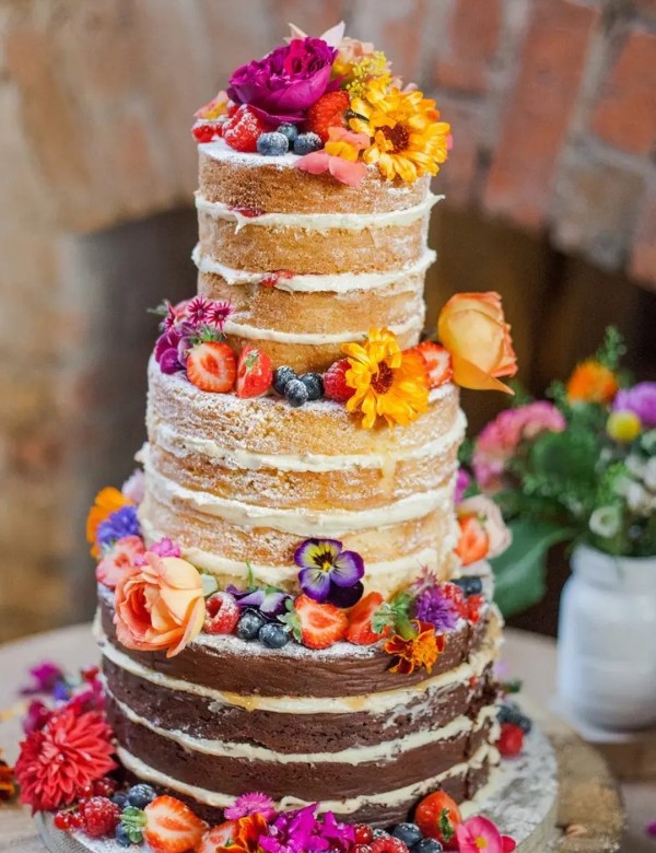 a colorful naked wedding cake topped with bright blooms and berries is a fantastic idea for a summer boho wedding with plenty of color