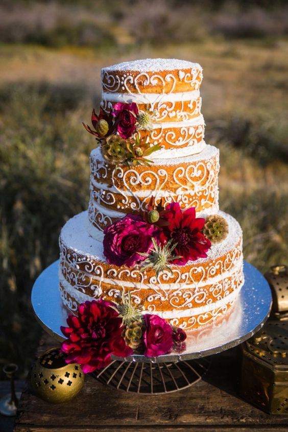 a creative naked wedding cake with sugar patterns, red and burgundy blooms and seed pods is a lovely idea for a boho wedding