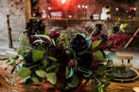 a dark burgundy and black rose wedding centerpiece with greenery and eucalyptus is classics for Halloween