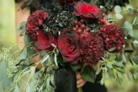 a dark wedding bouquet with black hydrangeas, red roses, berries and eucalyptus for a Halloween bride