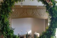 a faux fireplace, a greenery round altar with blooms and candles on stumps and hanging down from the wreath