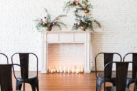 a faux fireplace in front of a whitewashed brick wall, candles and floral arrangements on the mantel for a beautiful look