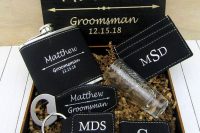 a groomsmen gift box with aknife, a bottle opener, a flask in a leather cover, a money clip and a wallet, all personalized