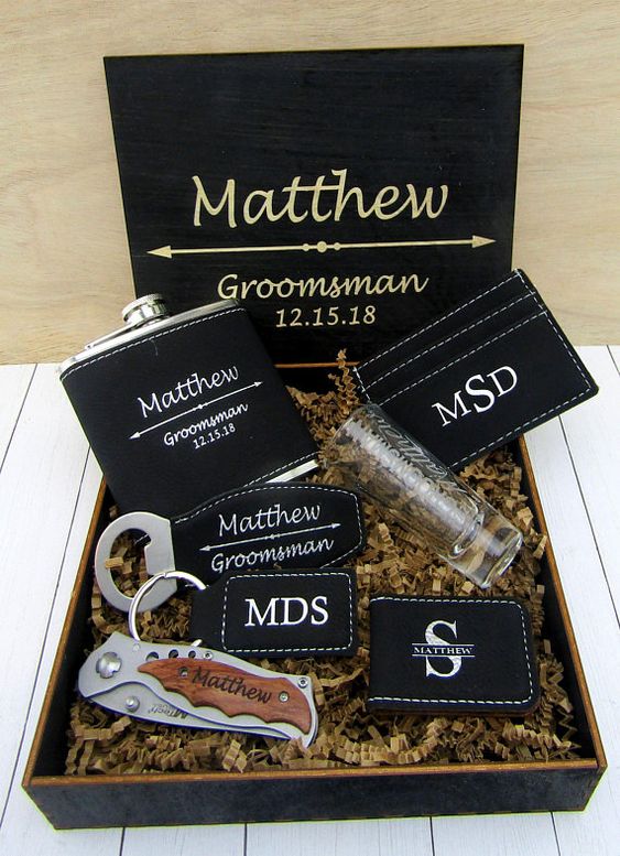 a groomsmen gift box with aknife, a bottle opener, a flask in a leather cover, a money clip and a wallet, all personalized