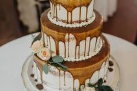 a lovely three-tier naked wedding cake with caramel drip, neutral blooms and greenery and a silver topper is a chic dessert